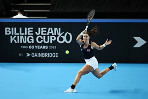 Jodie Burrage hitting a forehand on court in front of a Billie Jean King Cup advertisement board at the Copper Box Arena