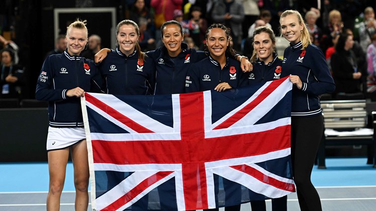 Harriet Dart, Heather Watson, Anne Keothavong, Maia Lumsden, Jodie Burrage and Katie Boulter holding the flag of Great Britain on court after qualifying for the 2024 Billie Jean King Cup Qualifiers