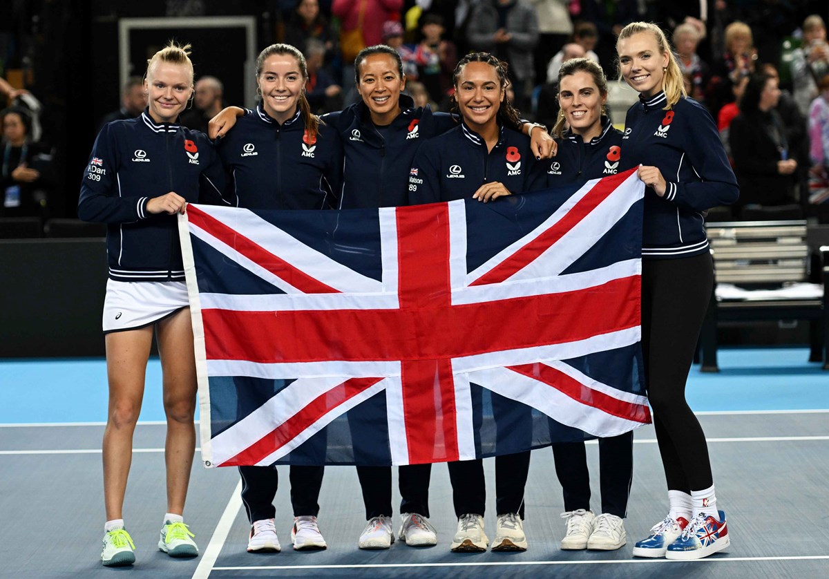 Harriet Dart, Heather Watson, Anne Keothavong, Maia Lumsden, Jodie Burrage and Katie Boulter holding the flag of Great Britain on court after qualifying for the 2024 Billie Jean King Cup Qualifiers