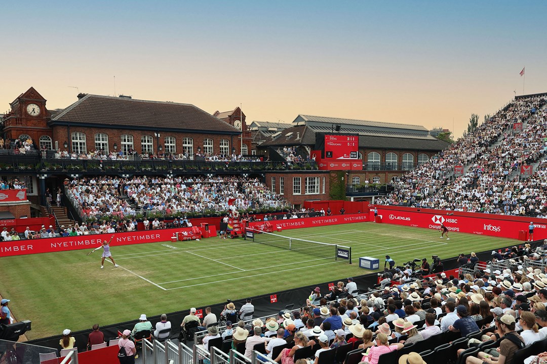 A view from the stands at the HSBC Championships  towards the Queen's Clubhouse while a player is serving on the grass court.