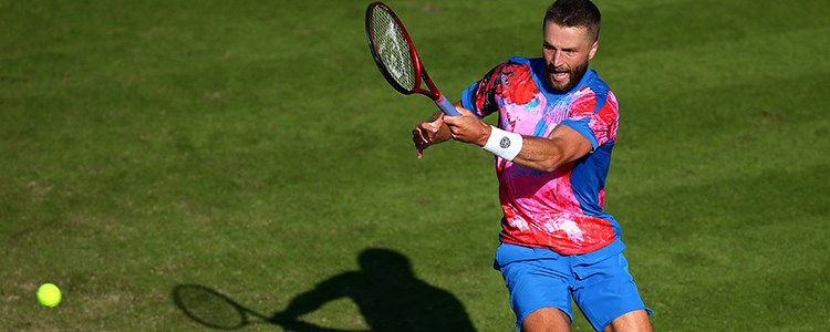 Liam Broady playing a forehanded shot on a tennis court