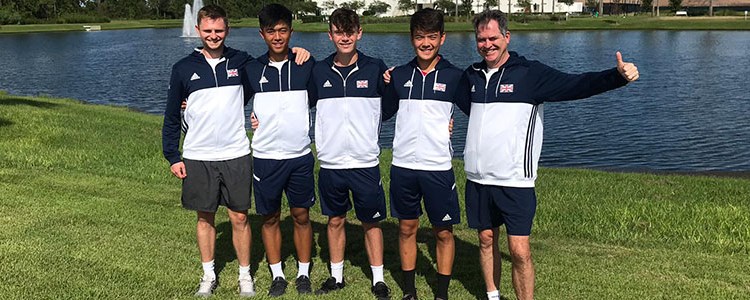 5 members of the GB team standing on grass in front of a pond with blue and white GB jackets on
