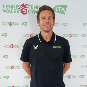 Chris posing for a picture with the LTA tennis wales  backdrop