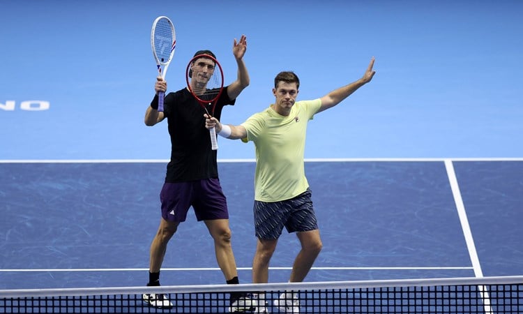 Joe Salisbury and Neal Skupski holding their hands and rackets in the air to wave to the crowd after securing their spot in the Nitto ATP Finals final