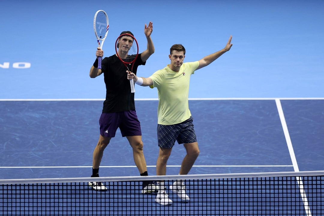 Joe Salisbury and Neal Skupski holding their hands and rackets in the air to wave to the crowd after securing their spot in the Nitto ATP Finals final