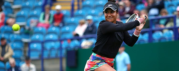 Heather Watson playing a double backhand shot in a tennis match with a crowd watching in the background