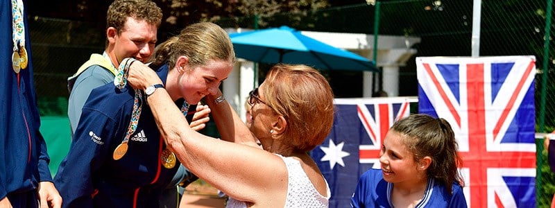 junior tennis player receiving medal around neck with GB flag in the background