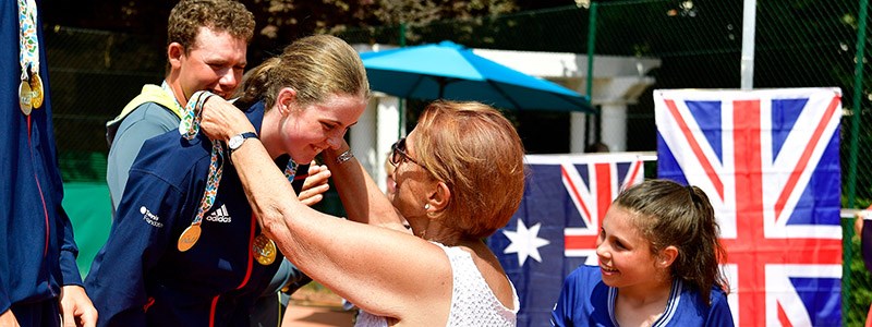 junior tennis player receiving medal around neck with GB flag in the background