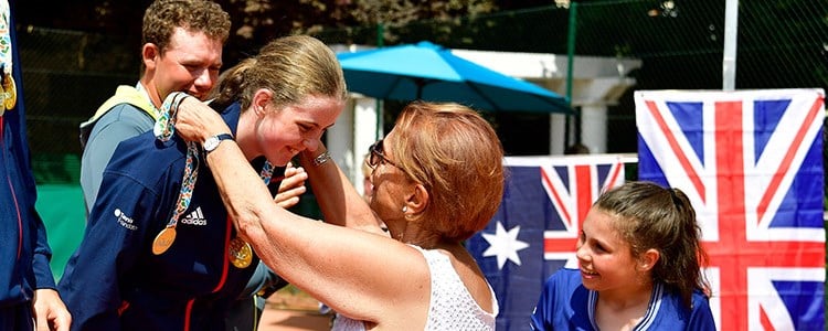 junior tennis player receiving medal around neck with GB flag in the background