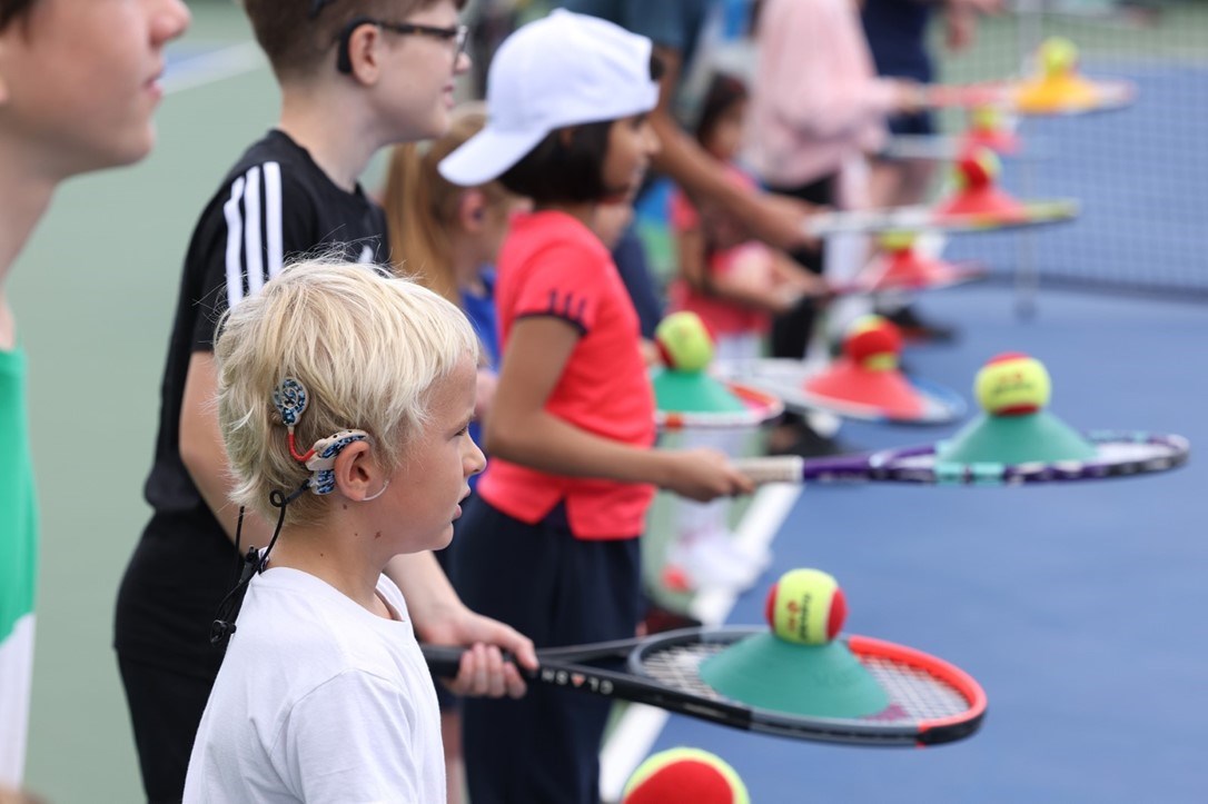 Kids lined up on the baseline for a tennis coaching session