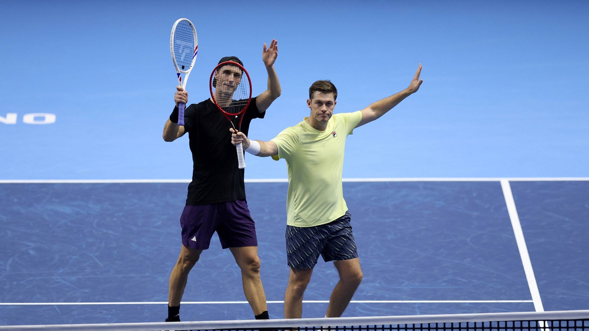 Joe Salisbury and Neal Skupski holding their hands and rackets in the air to wave to the crowd after securing their spot in the Nitto ATP Finals final