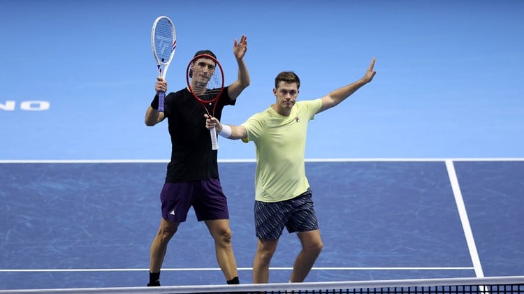 Joe Salisbury and Neal Skupski holding their hands and rackets in the air to wave to the crowd after securing their spot in the Nitto ATP Finals final