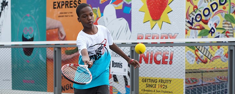 junior player wearing streetgames shirt hitting a forehand 
