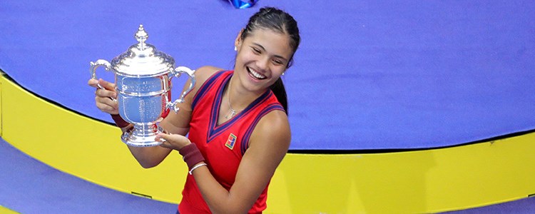Emma Raducanu smiling and holding the 2021 US Open trophy