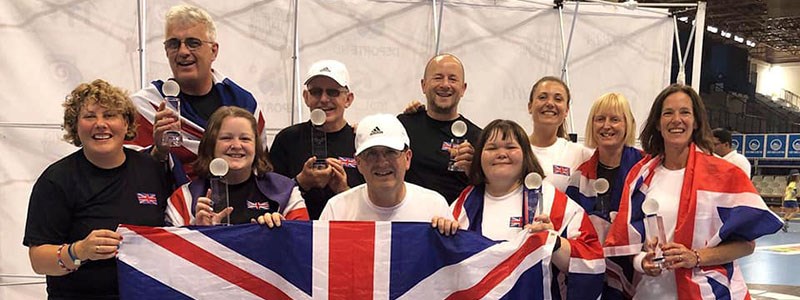 GB players holding winning trophies in hand and four of the players holding a large GB flag at the front