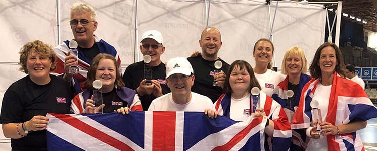 GB players holding winning trophies in hand and four of the players holding a large GB flag at the front