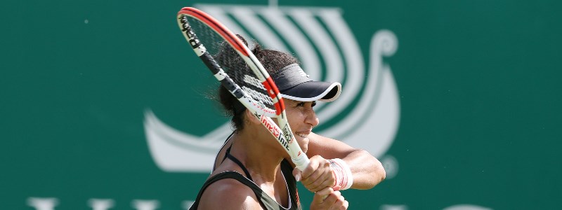 Heather Watson playing a double forehand shot in front of a green backboard