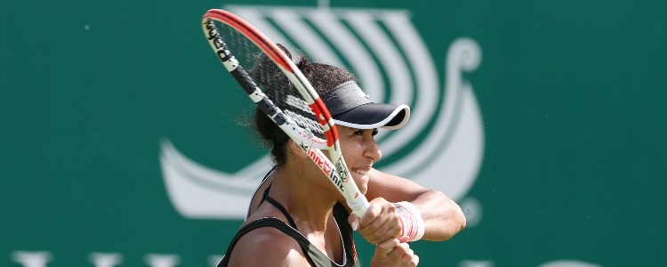 Heather Watson playing a double forehand shot in front of a green backboard