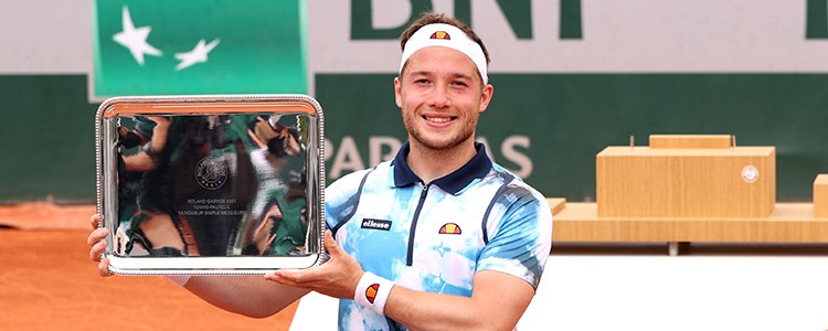 Alfie Hewett holding a trophy on a tennis court