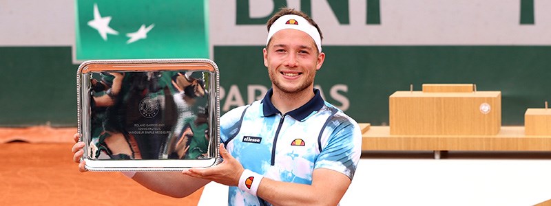 Alfie Hewett holding a trophy on a tennis court