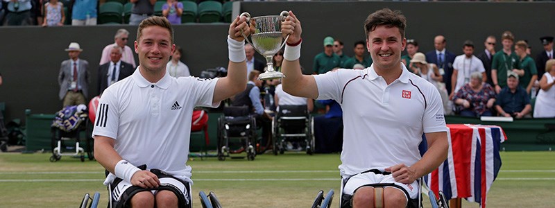 alfie hewett and gordon reid holding trophy in air on court at wimbledon