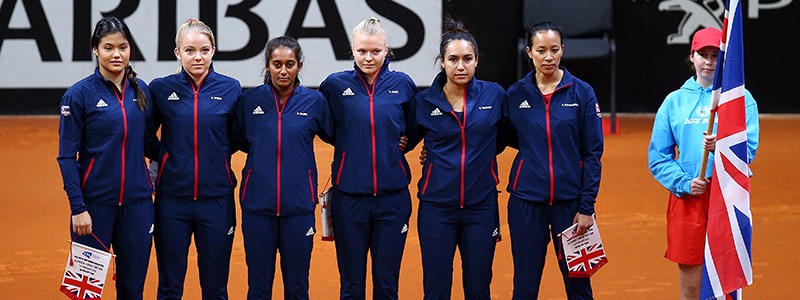 The whole 2020 Fed Cup Team standing side-by-side on a clay tennis court