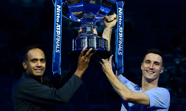 Rajeev Ram and Joe Salisbury both holding the Nitto ATP trophy while smiling on court