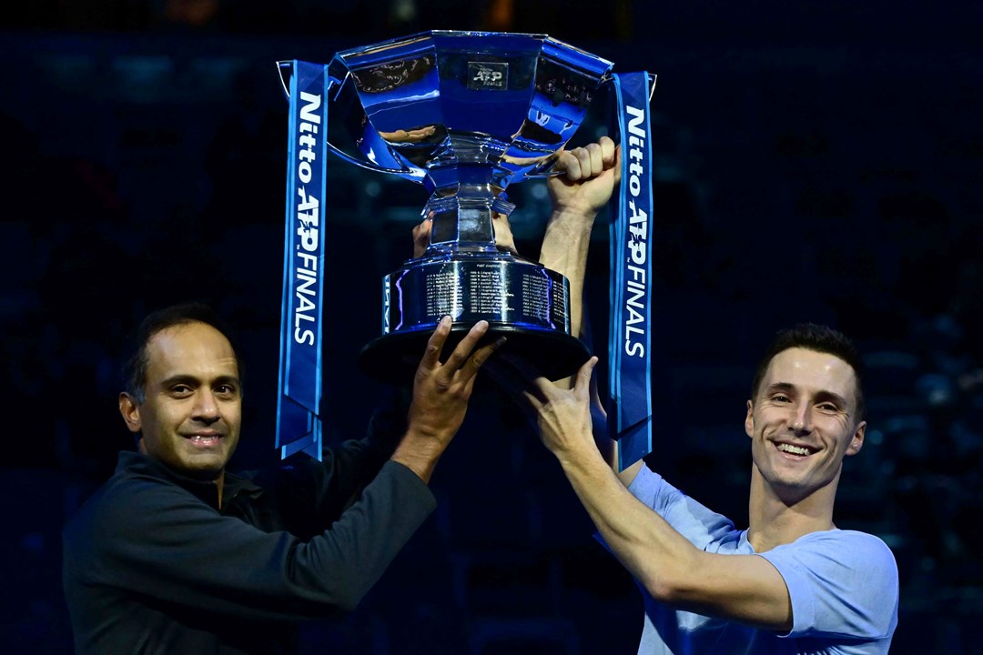 Rajeev Ram and Joe Salisbury both holding the Nitto ATP trophy while smiling on court