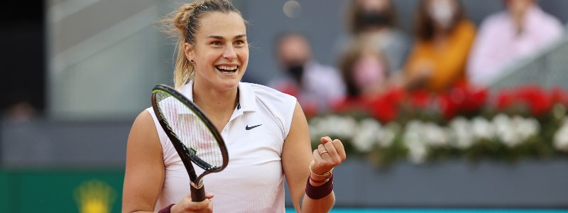 Aryna Sabalenka smiling whilst holding a tennis racket