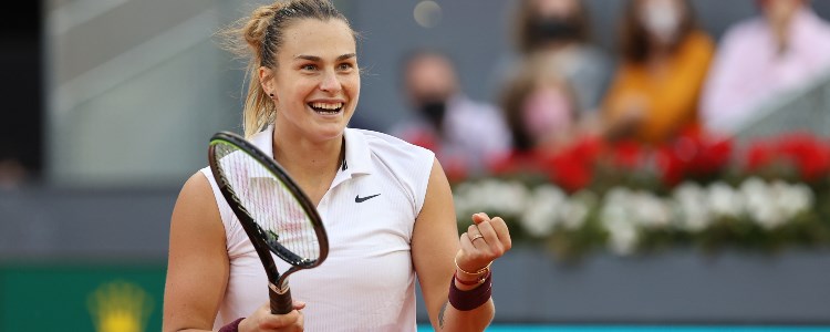 Aryna Sabalenka smiling whilst holding a tennis racket