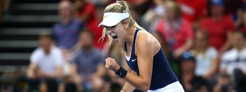 Katie Boulter passionately celebrating in front of a blurred audience in a tennis court