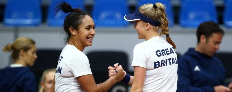 Heather Watson and Harriet Dart shaking hands and smiling in front of people blurred out in the background