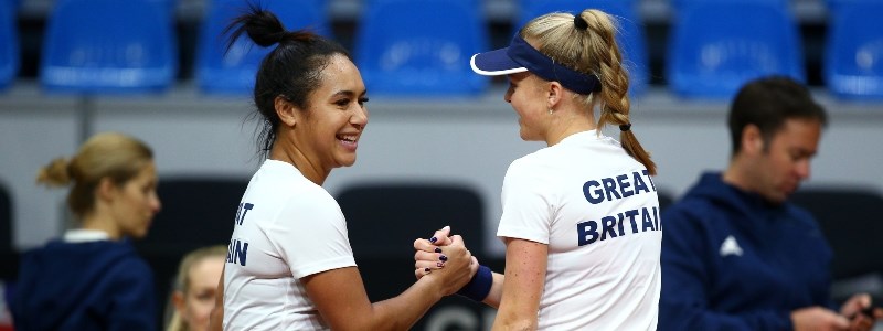 Heather Watson and Harriet Dart shaking hands and smiling in front of people blurred out in the background