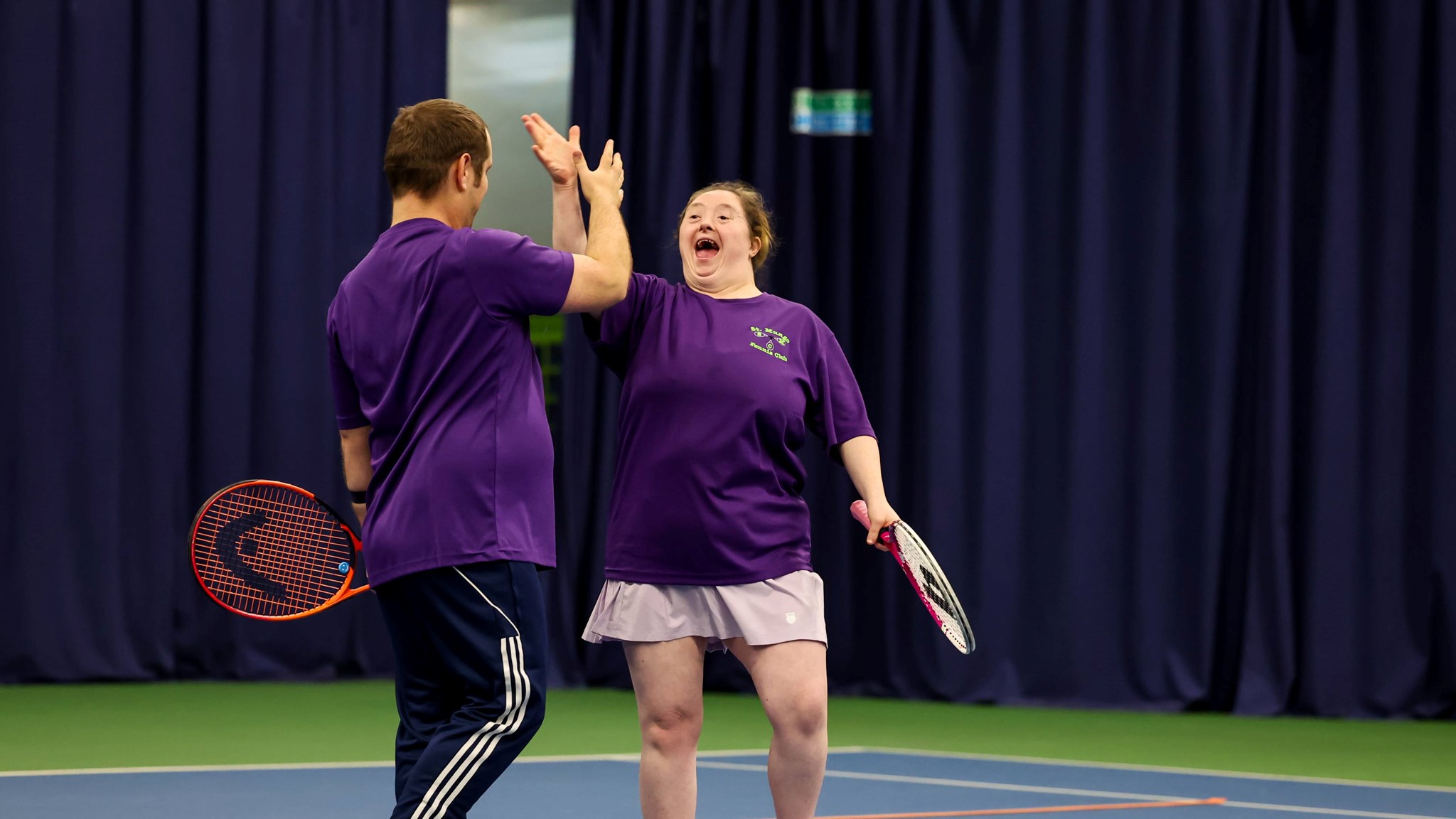 Two players high fiving at the 2025 Learning Disability Tennis National Finals