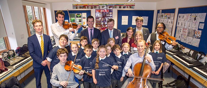 tim henman standing besides school kids in a classroom with few children holding violins at Reed’s School in Cobham, Surrey 