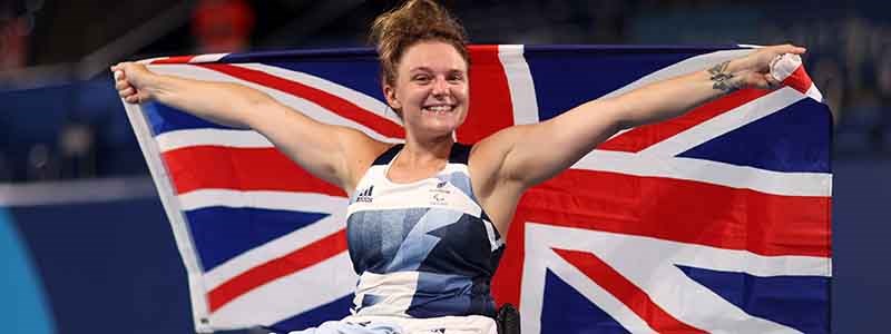 jordanne whiley celebrating holding up large GB flag behind her