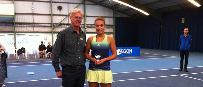 freya christie standing on court with trophy in hand next to presenter