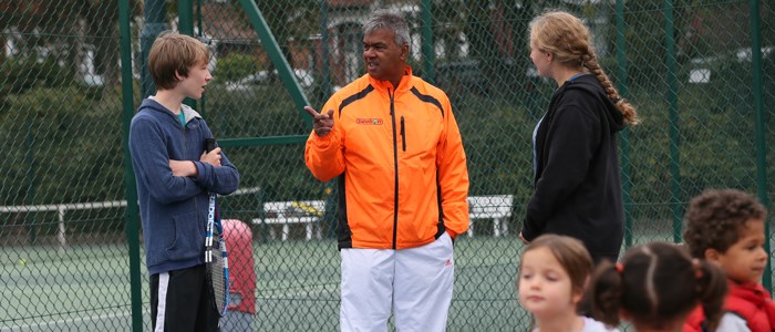 robby sukhdeo wearing orange jacket talking to players outside Albert Park court
