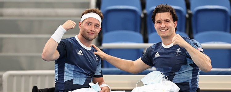Alfie Hewett and Gordon Reid smiling together in their tennis gear pitchside next to the seats