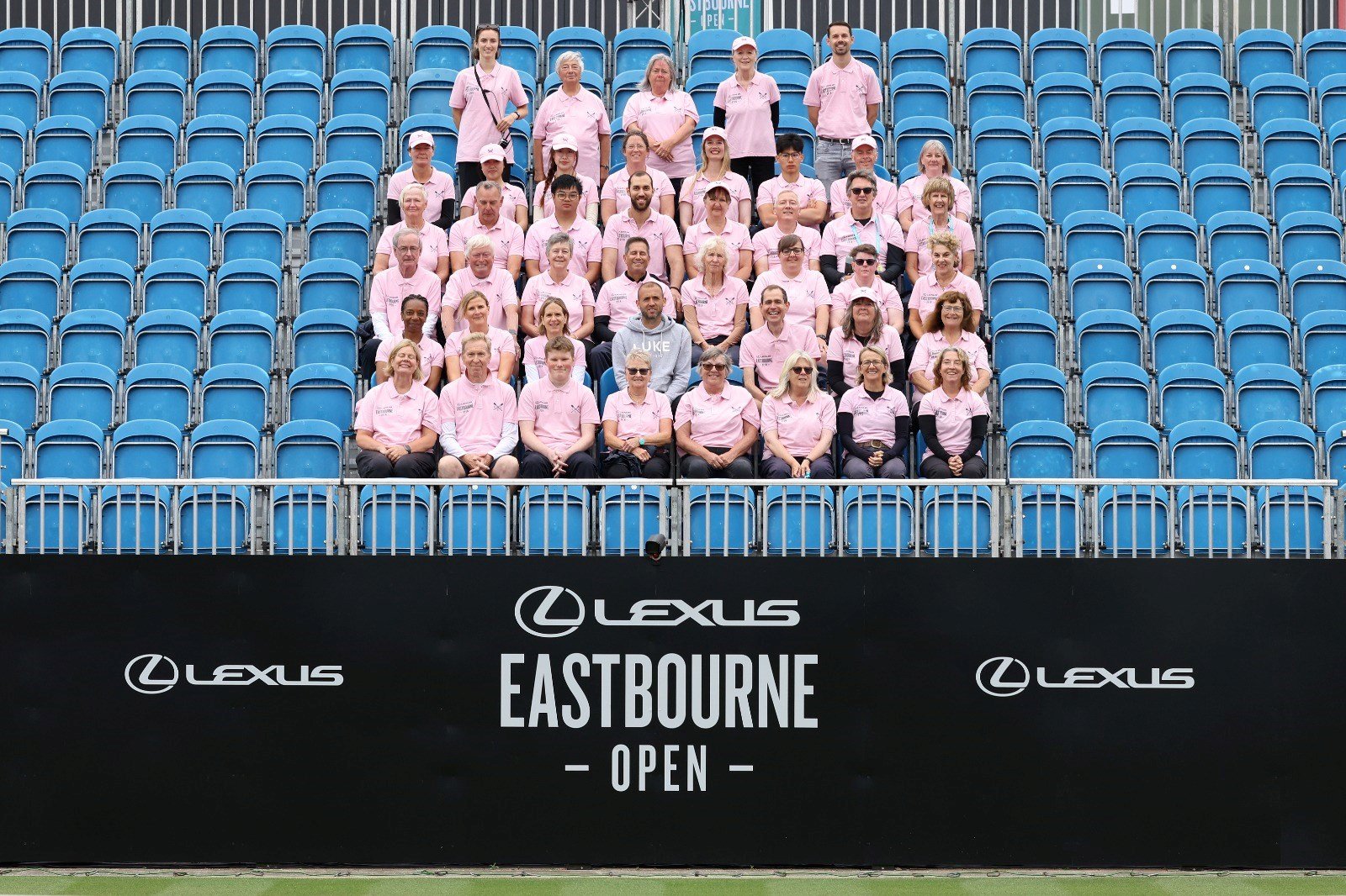 The Lexus Eastbourne Open team sitting in the stands in front of the event signage