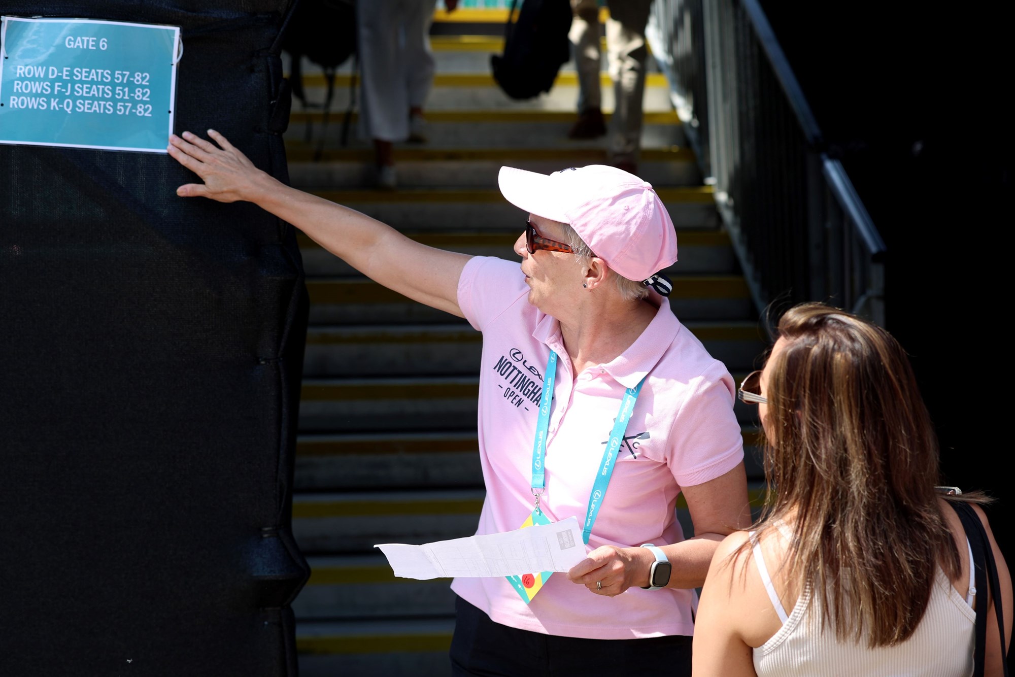 A female volunteer at the Lexus Eastbourne Open standing at the entrance to Centre Court directing an attendee to her seat