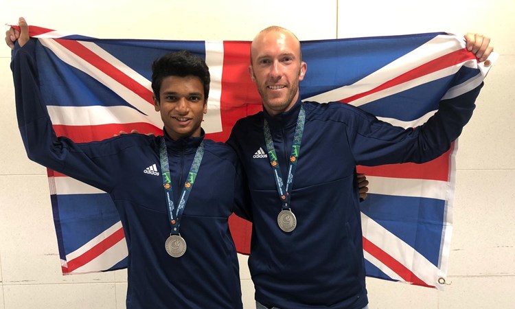 Esah Hayat and Lewis Fletcher pose behind union jack flag with their medals