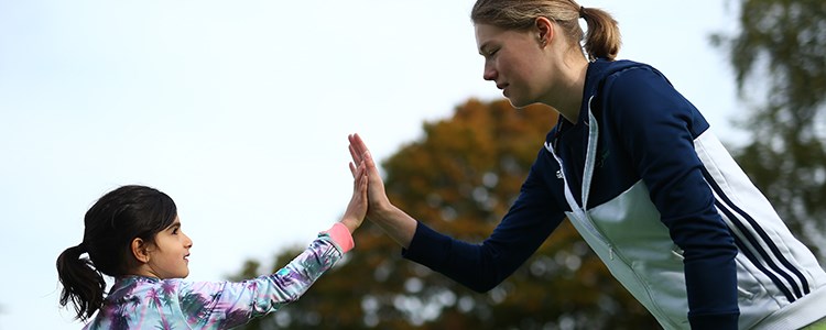 kid hi-fiving with adult coach