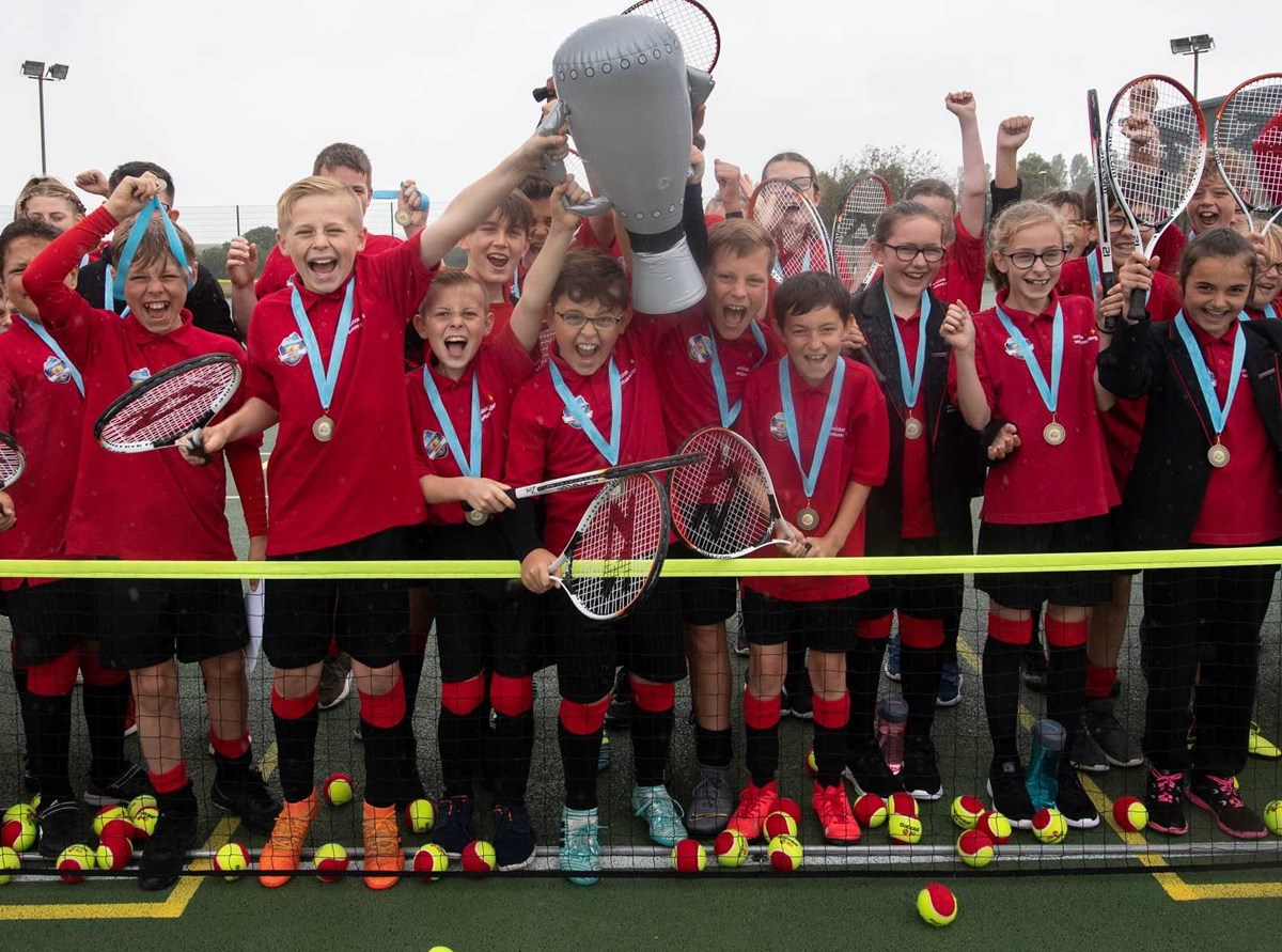 Youth tennis class posing with an inflatable trophy