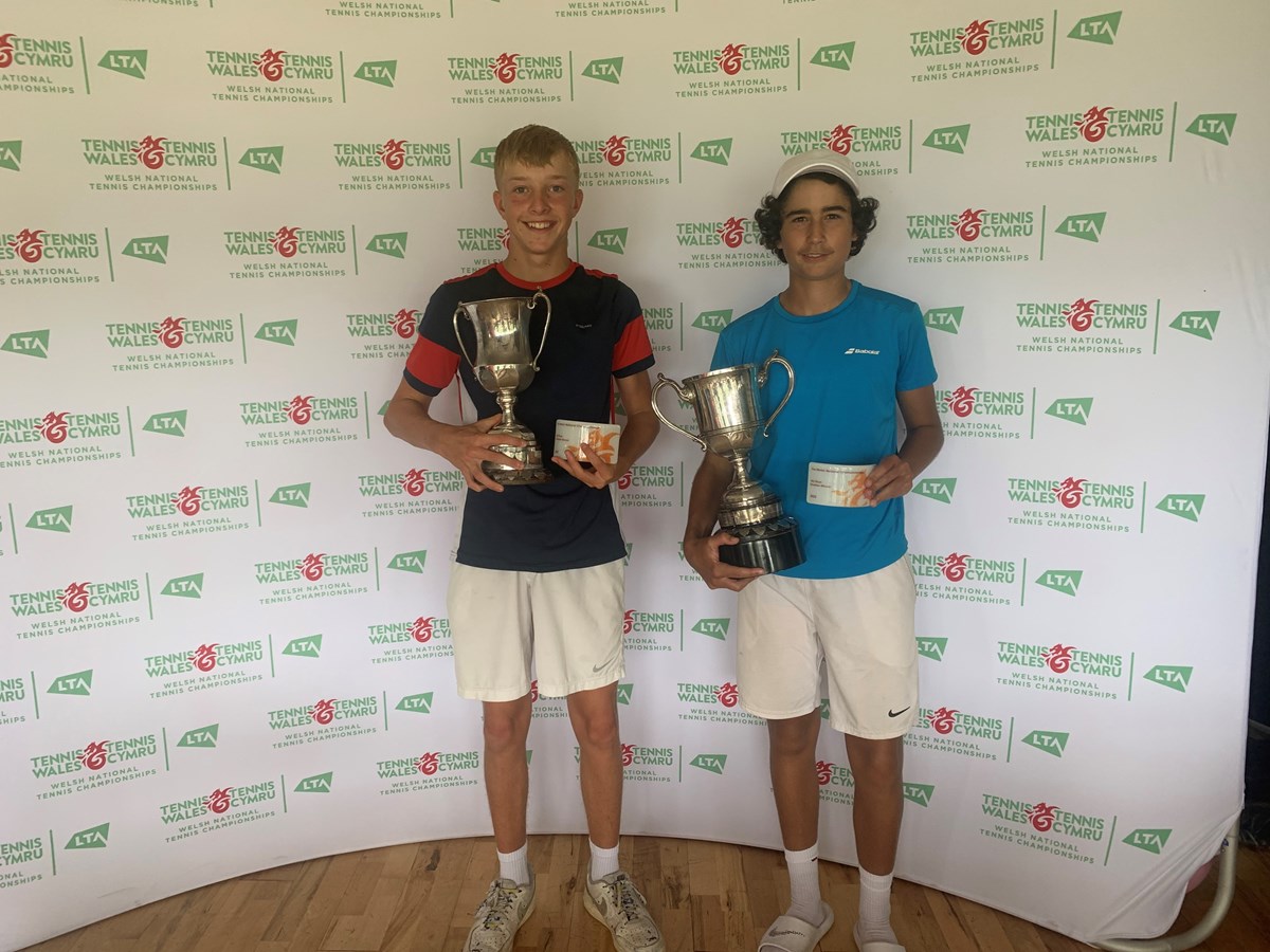 Two boys posing with a tennis award against the tennis wales backdrop