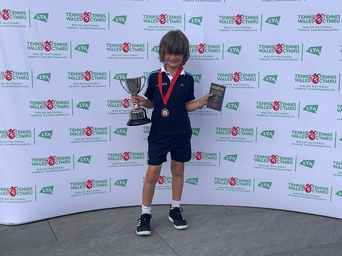 Young tennis champion posing with a award