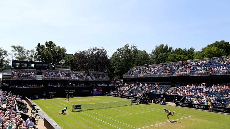A lawn court tennis match with a stadium full of audience