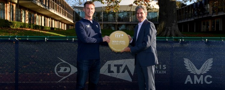 two men hlding gold standard ITF trophy between them outside the LTA building