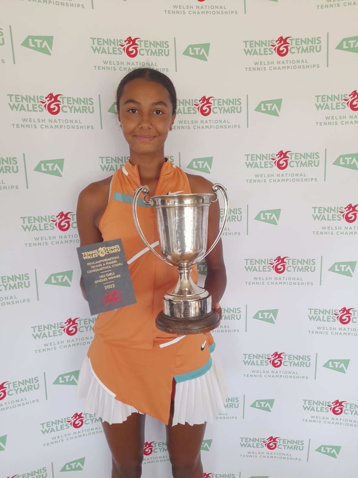 Girl posing with her tennis award infront of the tennis wales backdrop