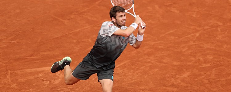 Cam Norrie mid swing on clay court